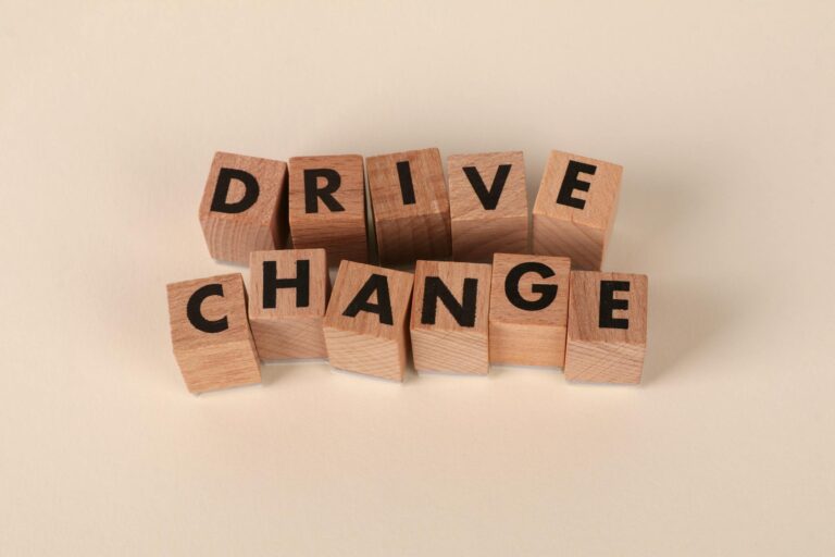 Wooden blocks spelling 'Drive Change' on a neutral background, symbolizing motivation and growth.